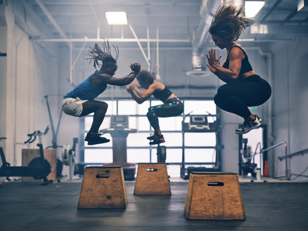 People doing box jumps in a gym